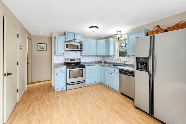 kitchen with blue cabinetry, tasteful backsplash, sink, light wood-type flooring, and stainless steel appliances