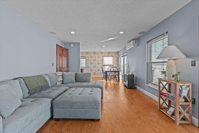 living room featuring a textured ceiling, wood-type flooring, and a wall mounted air conditioner