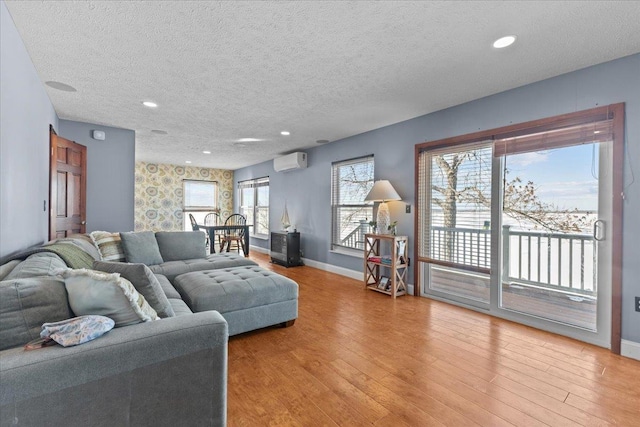 living room with a textured ceiling, a wall unit AC, and a healthy amount of sunlight