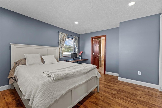 bedroom with dark hardwood / wood-style floors and a textured ceiling