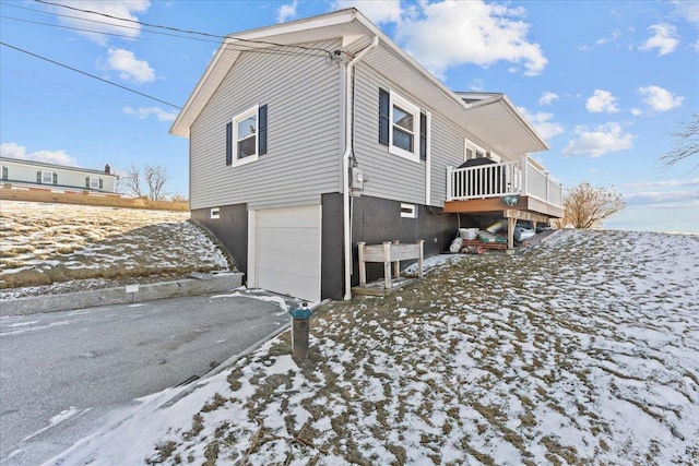 view of snowy exterior featuring a garage and a wooden deck