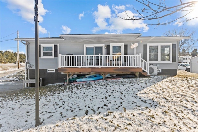 snow covered house with a deck and ac unit