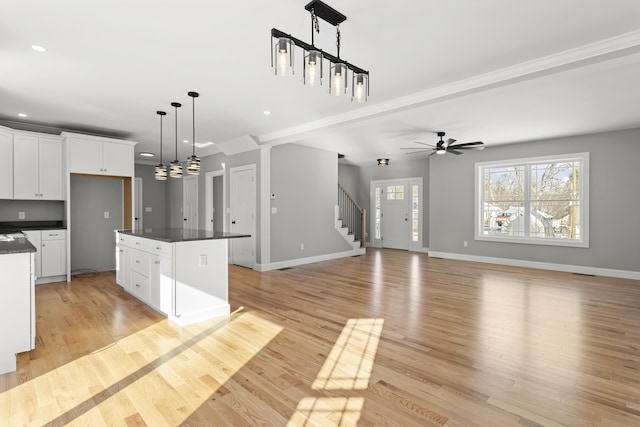 kitchen with white cabinetry, decorative light fixtures, a center island, and light hardwood / wood-style flooring