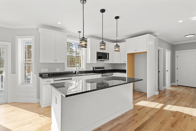 kitchen with pendant lighting, stainless steel appliances, white cabinets, and a kitchen island