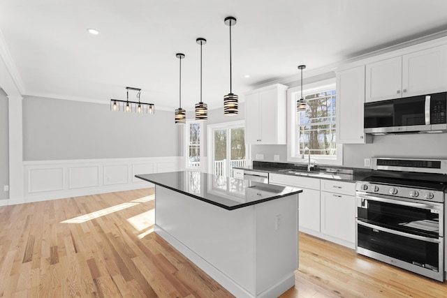 kitchen featuring white cabinetry, decorative light fixtures, appliances with stainless steel finishes, a kitchen island, and light hardwood / wood-style floors