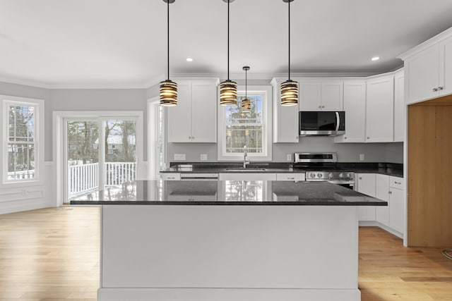 kitchen with light hardwood / wood-style flooring, hanging light fixtures, stainless steel appliances, white cabinets, and a kitchen island