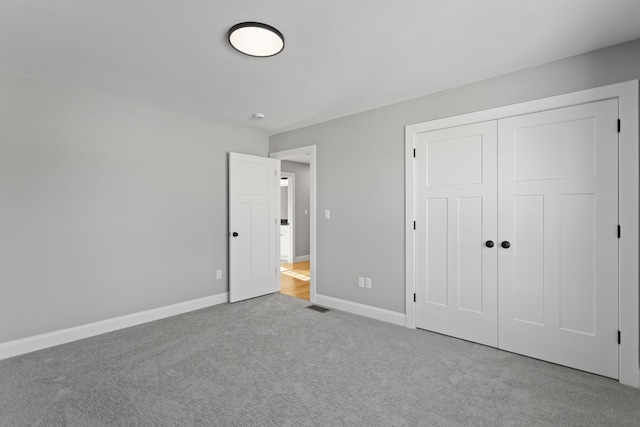 unfurnished bedroom with light colored carpet and a closet