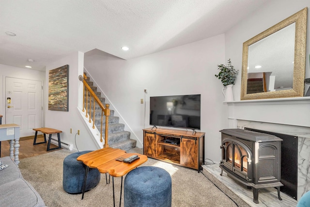 living room with carpet floors, a wood stove, and a textured ceiling