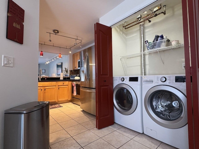 clothes washing area with light tile patterned floors, rail lighting, sink, and washer and clothes dryer