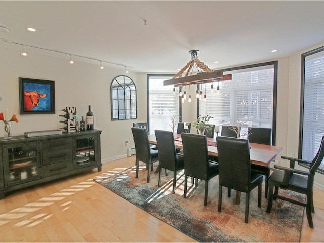 dining space with light hardwood / wood-style floors, a baseboard heating unit, and track lighting