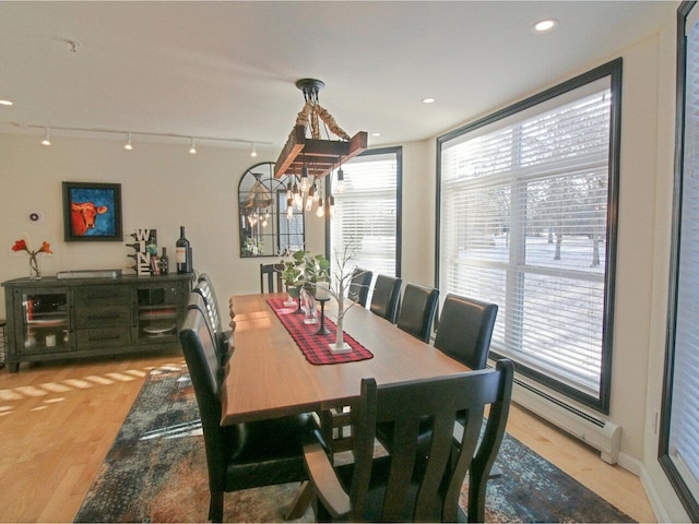 dining area with a baseboard radiator, a wealth of natural light, track lighting, and light wood-type flooring