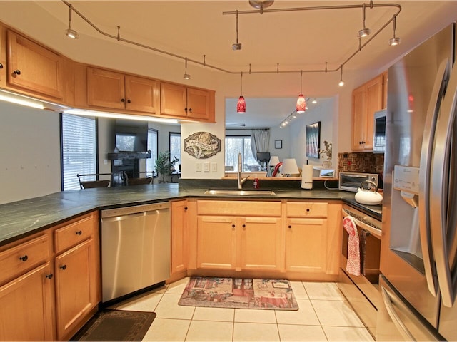 kitchen with track lighting, stainless steel appliances, sink, kitchen peninsula, and light tile patterned floors