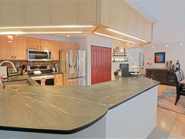 kitchen with decorative backsplash, sink, kitchen peninsula, stainless steel appliances, and light brown cabinets