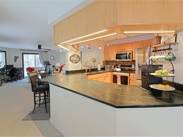 kitchen with sink, stainless steel appliances, kitchen peninsula, and light brown cabinetry