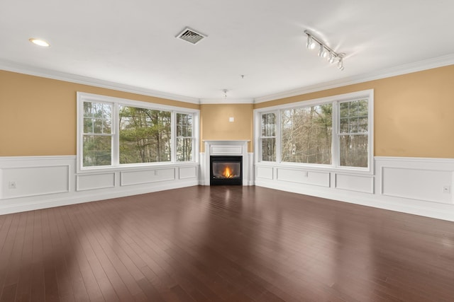 unfurnished living room featuring rail lighting, wood-type flooring, and ornamental molding