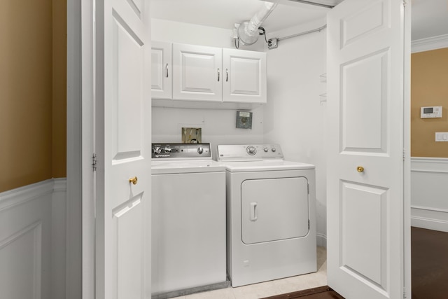 laundry room with washing machine and clothes dryer, ornamental molding, and cabinets