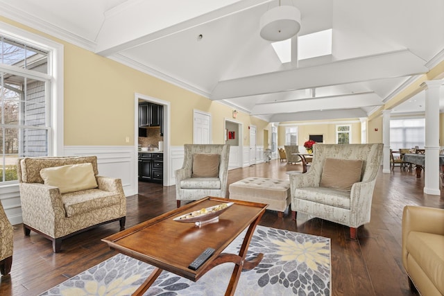 living room with decorative columns, dark hardwood / wood-style flooring, crown molding, and lofted ceiling with beams