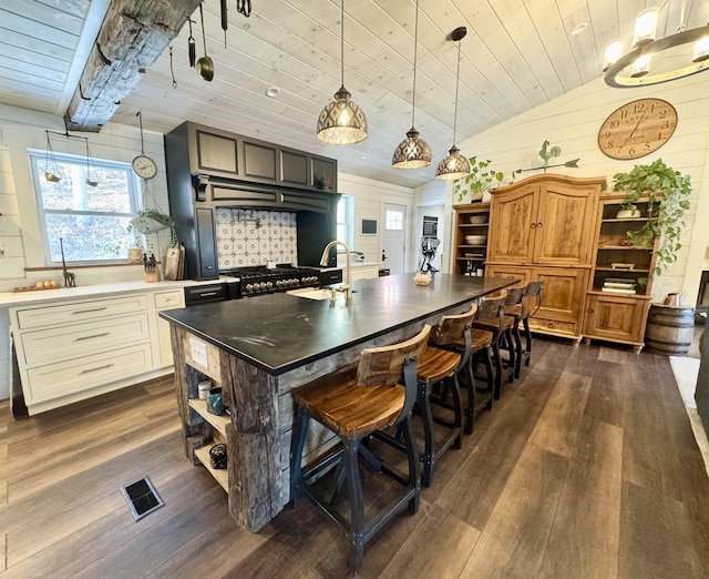 kitchen with wood ceiling, a kitchen island with sink, sink, dark wood-type flooring, and lofted ceiling