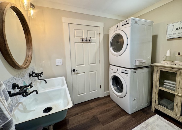 laundry room with sink, crown molding, dark hardwood / wood-style flooring, and stacked washing maching and dryer