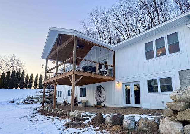 snow covered rear of property with a deck and french doors