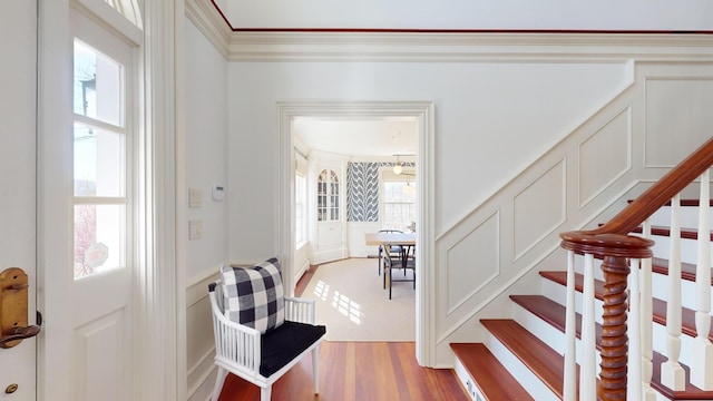 foyer with ornamental molding and light hardwood / wood-style floors