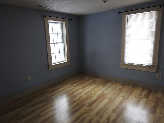 unfurnished room featuring a textured ceiling and light wood-type flooring