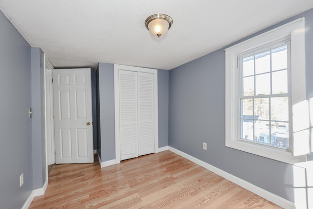 unfurnished bedroom with light hardwood / wood-style floors, a closet, and a textured ceiling