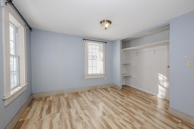 unfurnished bedroom featuring a textured ceiling, a closet, and light hardwood / wood-style flooring