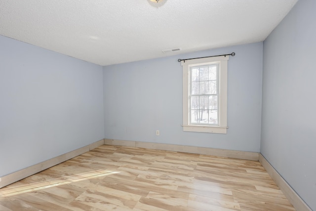 unfurnished room featuring light hardwood / wood-style floors and a textured ceiling