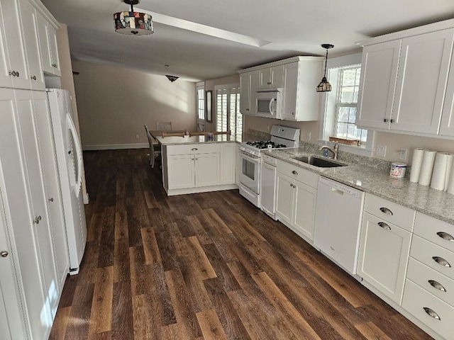 kitchen featuring white appliances, white cabinetry, sink, decorative light fixtures, and kitchen peninsula