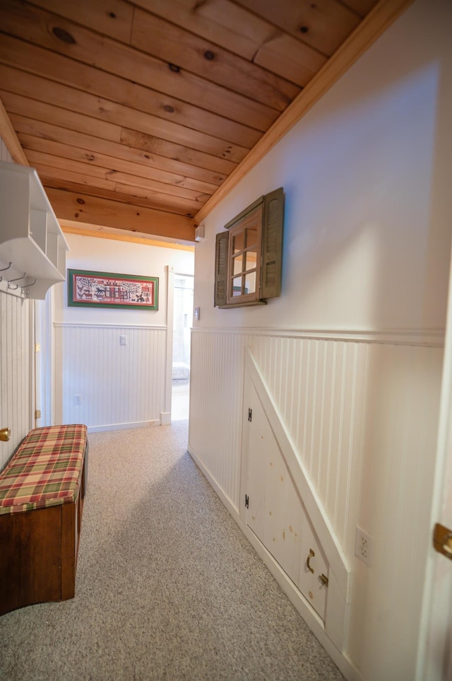 hall with crown molding, wooden ceiling, and light colored carpet