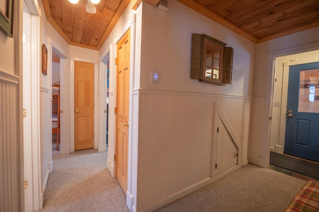 hallway featuring light colored carpet, wooden ceiling, and crown molding