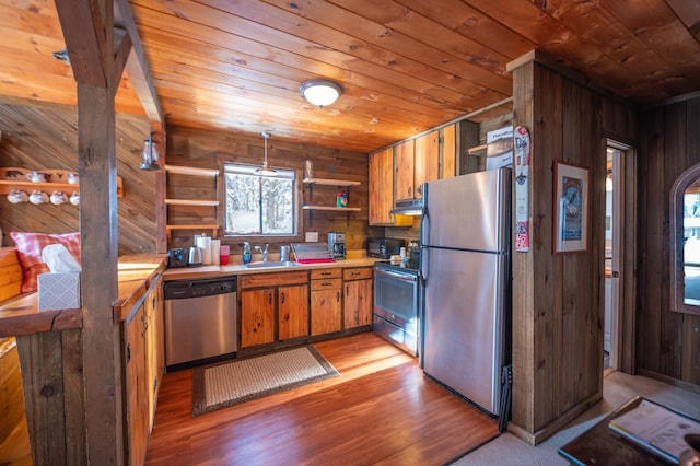 kitchen with sink, wooden walls, appliances with stainless steel finishes, and wooden ceiling