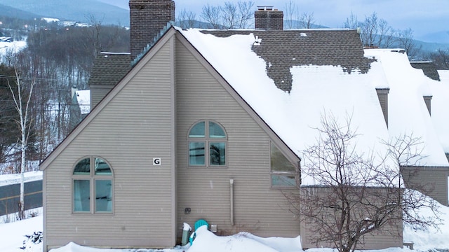 snow covered back of property featuring a mountain view and central air condition unit