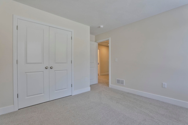 unfurnished bedroom with light colored carpet and a closet