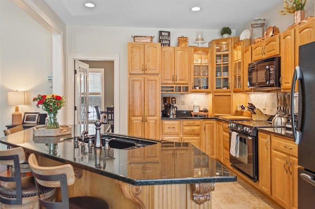 kitchen with tasteful backsplash, a kitchen breakfast bar, an island with sink, and black appliances