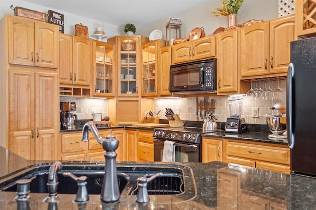 kitchen featuring dark stone countertops, backsplash, black appliances, and sink