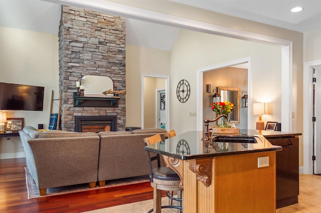 living room featuring wood-type flooring, lofted ceiling, sink, and a fireplace