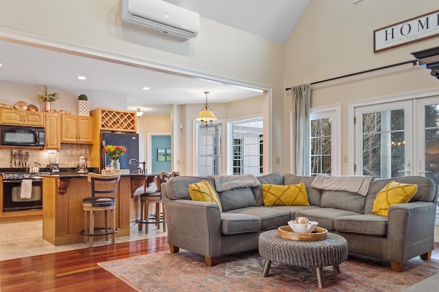 living room featuring lofted ceiling, sink, a wall mounted AC, and light hardwood / wood-style floors