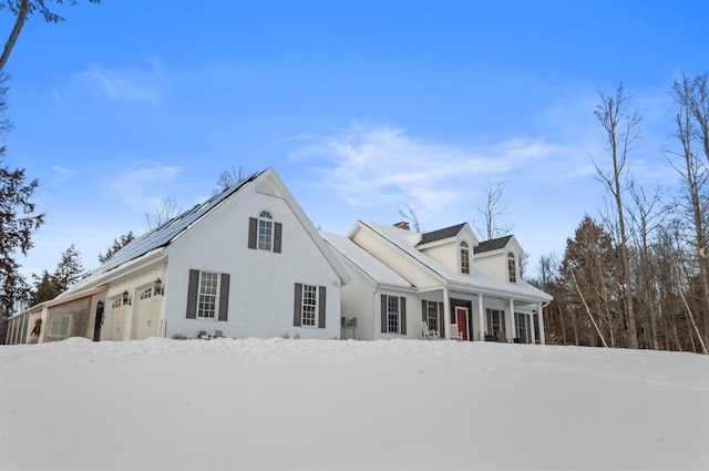 view of front of home featuring a garage, solar panels, and covered porch