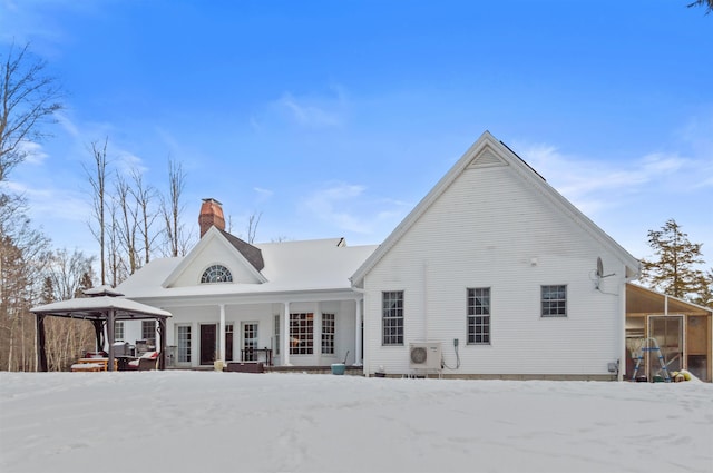 snow covered rear of property featuring a gazebo and ac unit