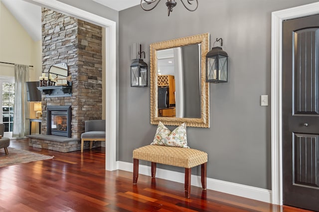 entrance foyer with vaulted ceiling, dark hardwood / wood-style floors, a notable chandelier, and a fireplace