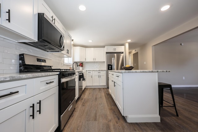 kitchen featuring a breakfast bar, white cabinetry, stainless steel appliances, dark hardwood / wood-style flooring, and decorative backsplash