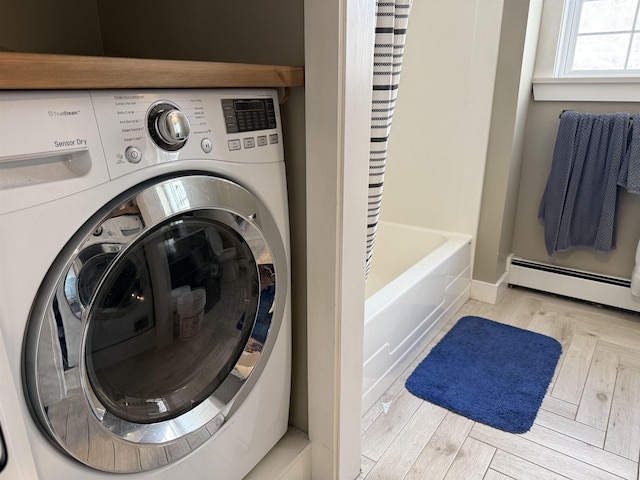 laundry area featuring a baseboard heating unit, laundry area, and washer / clothes dryer