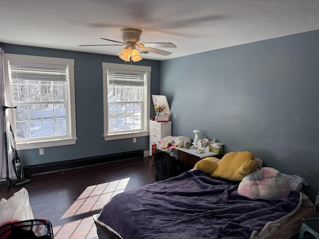 bedroom featuring a baseboard heating unit, baseboards, wood finished floors, and a ceiling fan