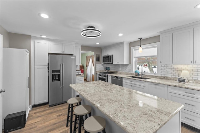 kitchen with pendant lighting, white cabinetry, sink, and premium appliances