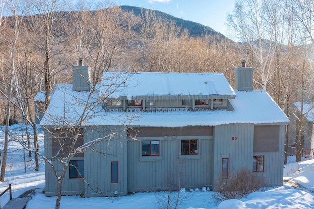 snow covered back of property featuring a mountain view