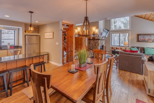 dining room with light hardwood / wood-style floors, plenty of natural light, and a stone fireplace