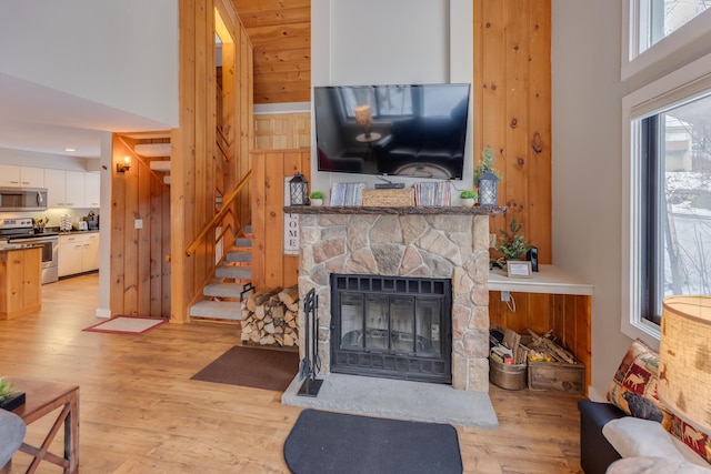 living room featuring a fireplace, light hardwood / wood-style flooring, and a high ceiling