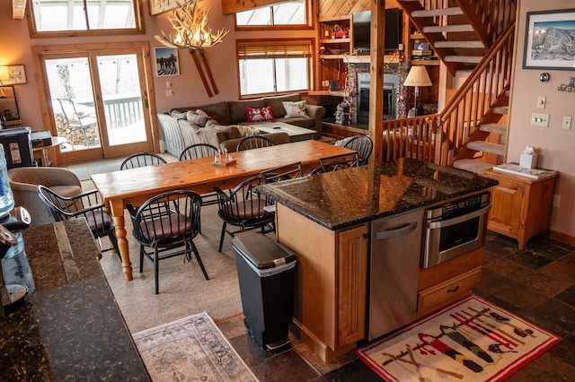 kitchen with an inviting chandelier, stainless steel oven, dark stone counters, and a towering ceiling